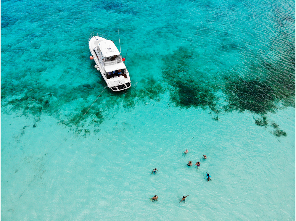 People enjoying a wonderful day at the beach with their yacht anchored nearby.